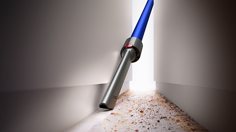 Using a Crevice Tool to vacuum out the dirt between two cabinets.